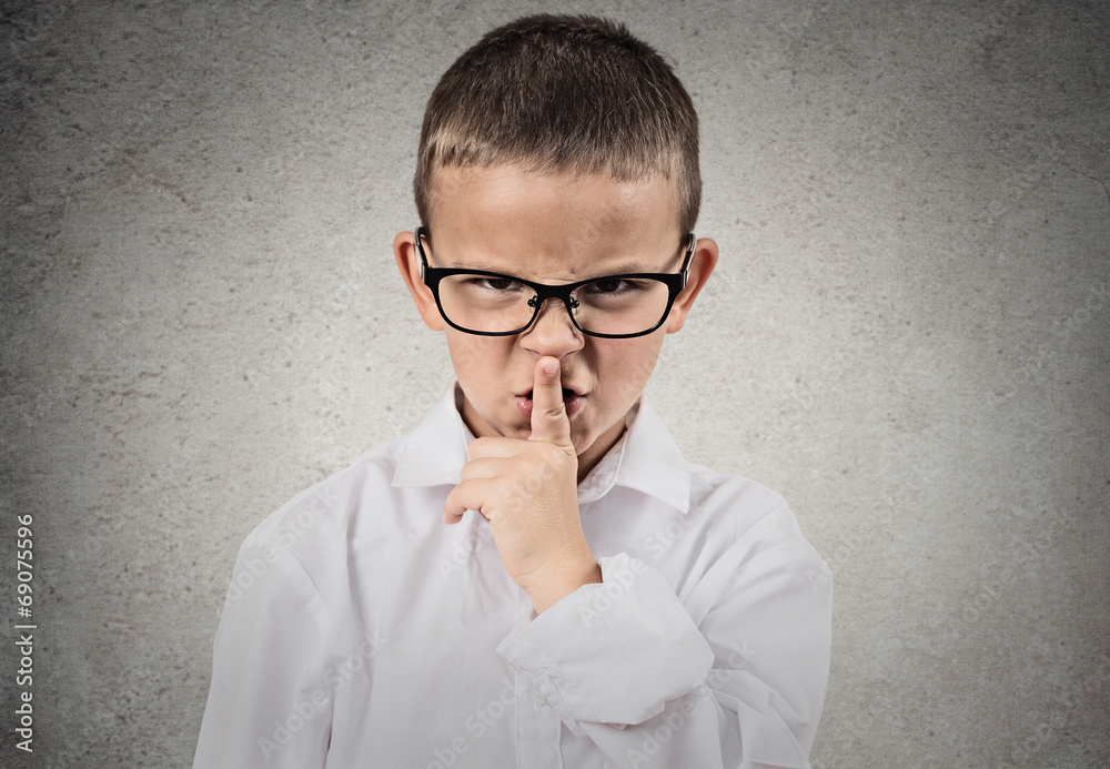 Boy giving be quiet gesture with finger on lips, grey background Boy giving be quiet gesture with finger on lips, grey background