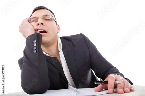 exhausted businessman sleeping at his desk yawning