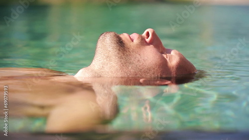 Man floating on water in swimming pool