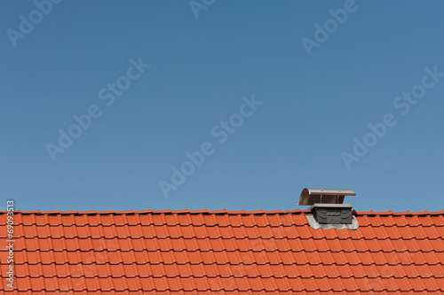 Ein neues Dach aus Tonziegeln mit Kaminabdeckung aus Edelstahl