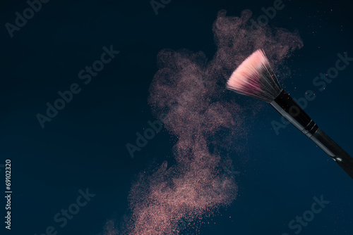 Professional black make-up brush with pink powder in motion isol