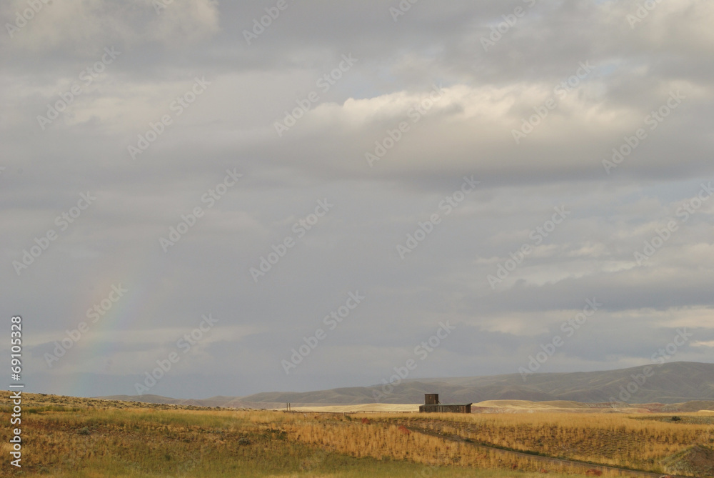 Nature landscape of fields and clouds with rainbow and hut