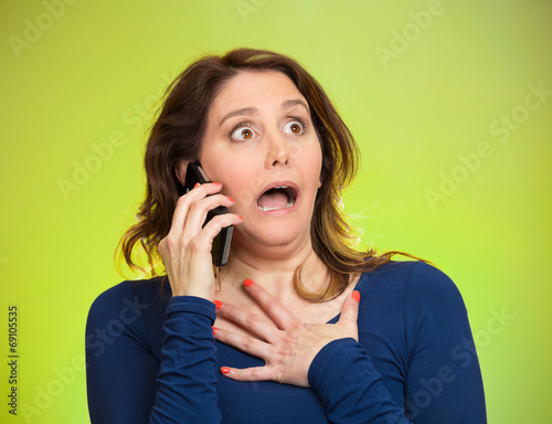 Slika na platnu Woman receiving shocking news on a phone, green background