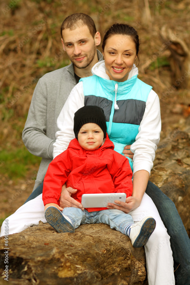 Beautiful young family lying on a blanket and looking at tablet