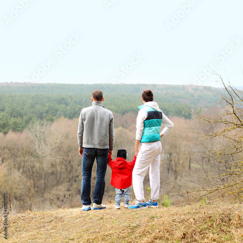 Beautiful young sporty familystands back on the mountain