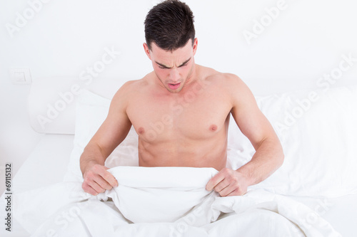  half naked young man in bed  looking down at his underwear