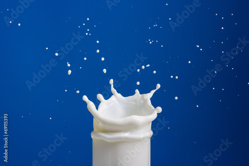 Splash of milk in a glass on a blue background.