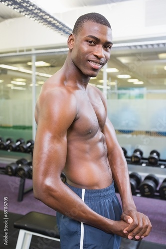 Shirtless young muscular man posing in gym