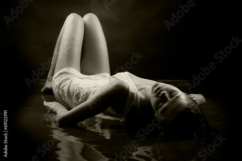 Girl in a white T-shirt lying in water on a black background.