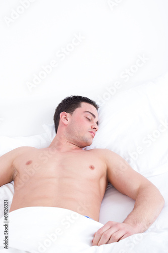 Young caucasian man sleeping in his bed at home