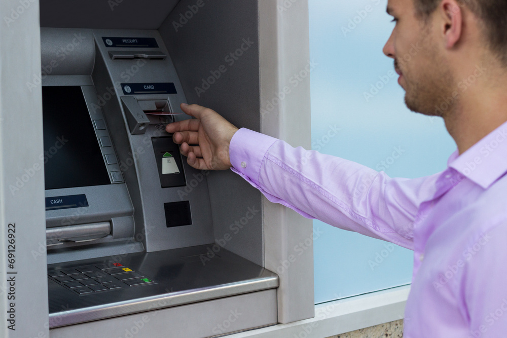 Man takes a credit card from an ATM Man takes a credit card from an ATM