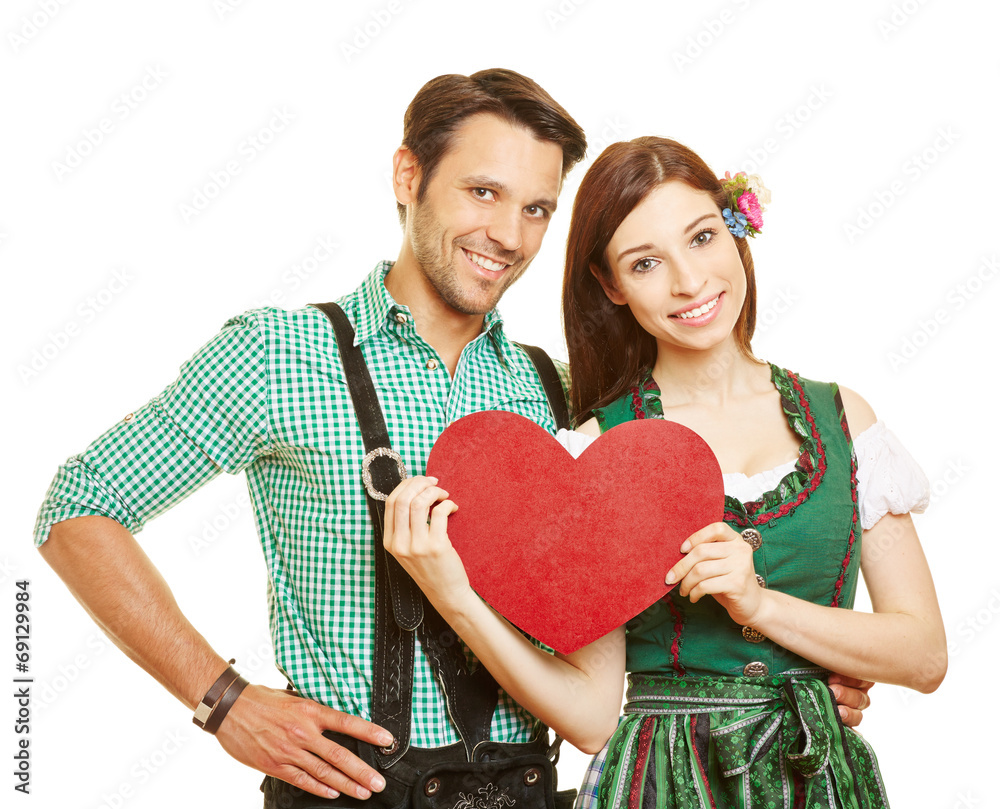 Paar in Tracht hält rotes Herz - obrazy, fototapety, plakaty 