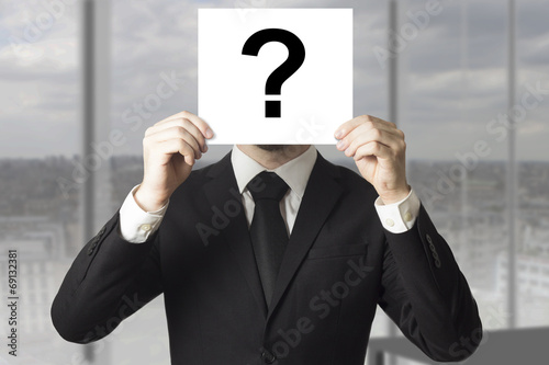 businessman hiding face behind sign question mark photo