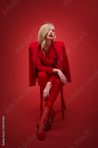 Stylish woman in red suit in studio