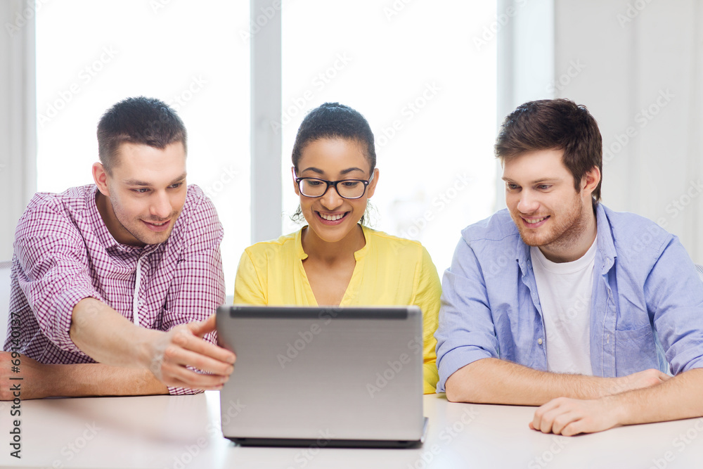 three smiling colleagues with laptop in office three smiling colleagues with laptop in office