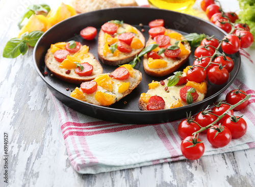 Tasty bruschetta with tomatoes on pan, on old wooden table