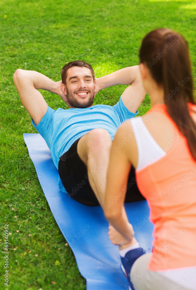 smiling man doing exercises on mat outdoors