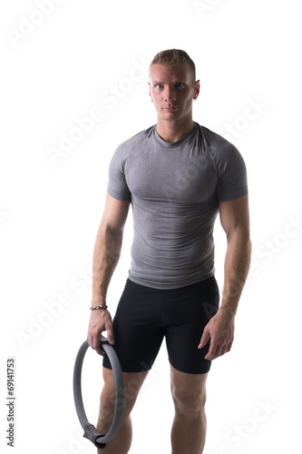 Young muscular man relaxed with Pilates ring in hand