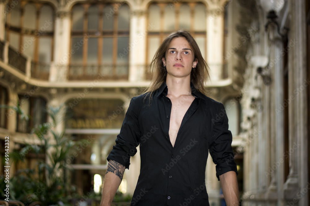 Handsome long hair young man indoors in elegant gallery Handsome long hair young man indoors in elegant gallery