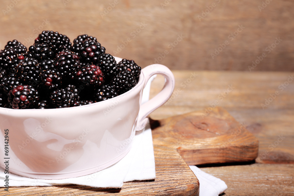 Sweet blackberries in color bowl on wooden background Sweet blackberries in color bowl on wooden background