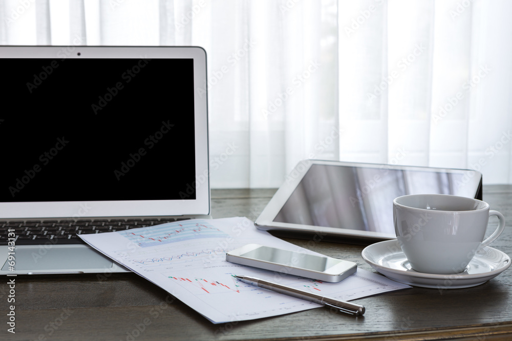 Laptop, tablet , smartphone and coffee cup with financial docume Laptop, tablet , smartphone and coffee cup with financial docume