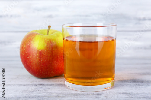 glass of apple juice and fresh apple on grey wooden table