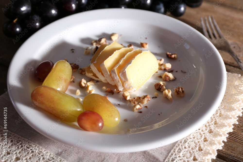 tasty grape and cheese on plate, on wooden table tasty grape and cheese on plate, on wooden table