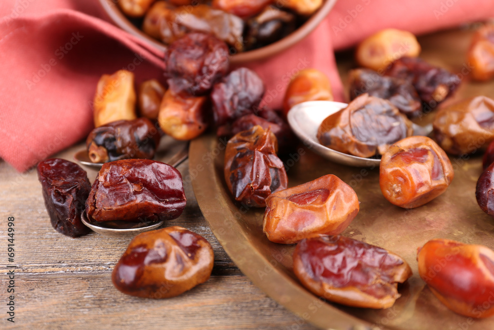 Tasty dates fruits on old metal tray, on wooden background Tasty dates fruits on old metal tray, on wooden background