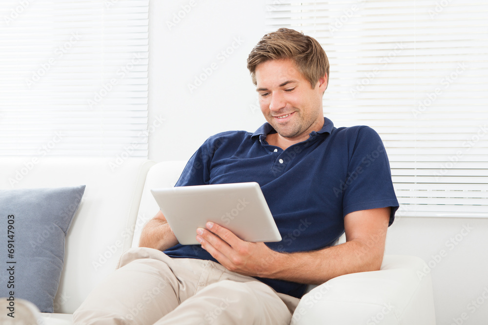 Relaxed Man Using Digital Tablet In Living Room Relaxed Man Using Digital Tablet In Living Room