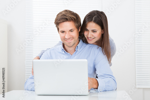 Surprised Man Looking At Woman While Using Laptop