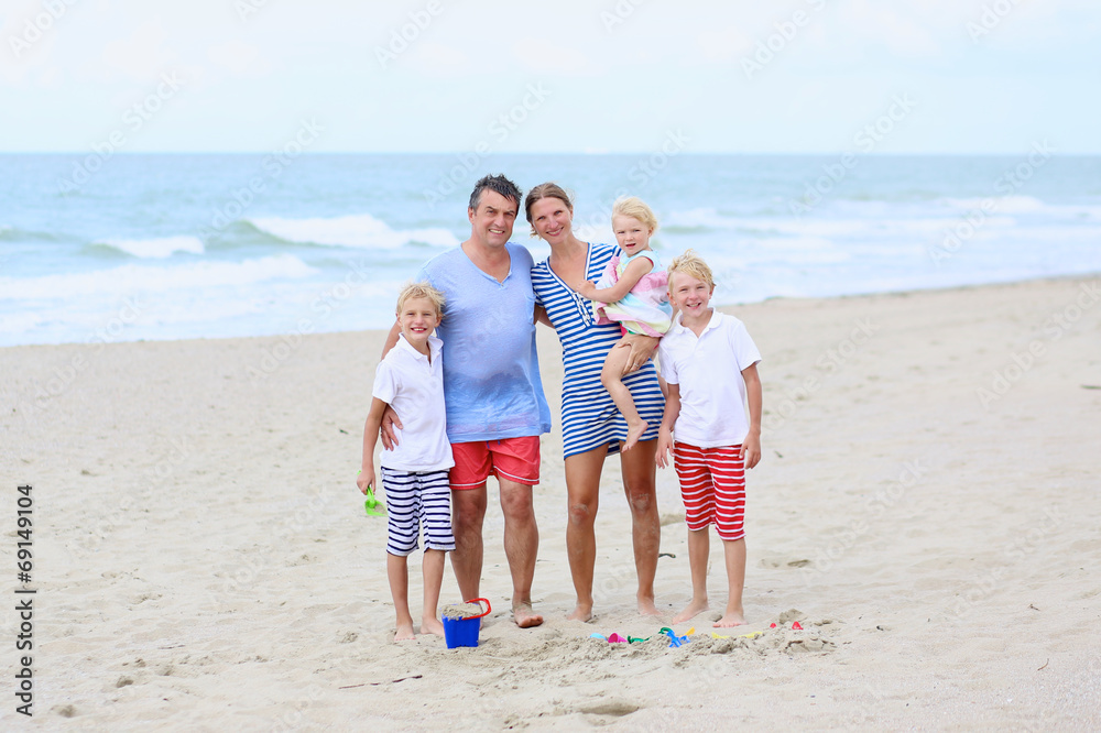 Happy family of five enjoying vacation on the beach