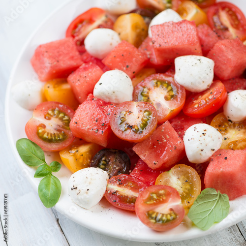 Salad with watermelon cubes, tomatoes and mozzarella, close-up