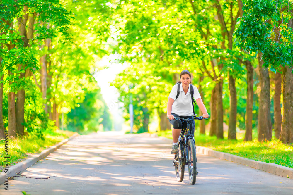 young girl on a bicycle in a park in the early morning