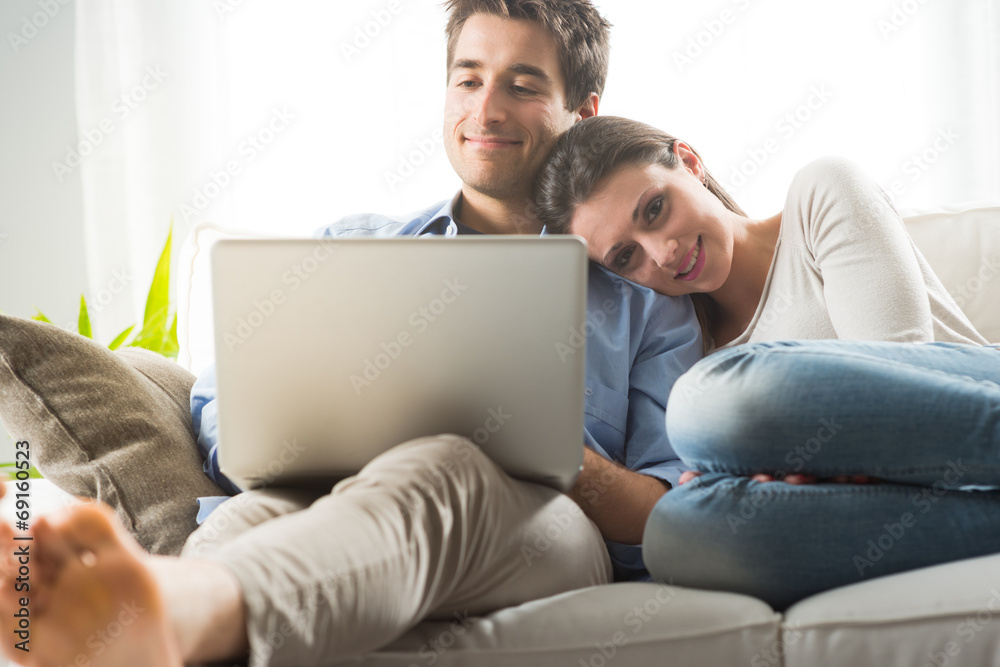 Couple relaxing on sofa with laptop Couple relaxing on sofa with laptop