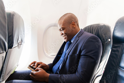 Фотография african airplane passenger using smart phone on plane