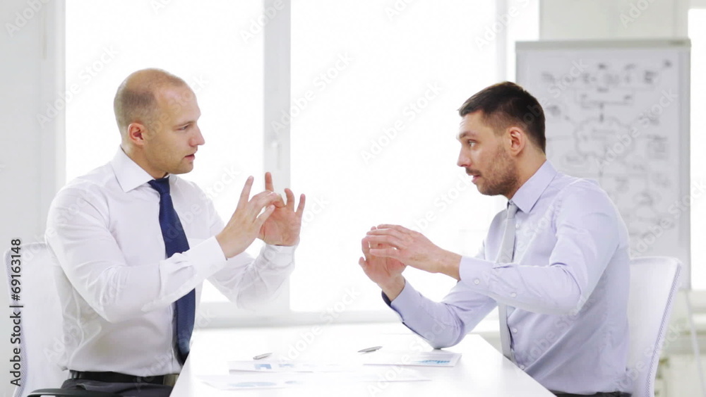 two smiling businessmen with charts in office