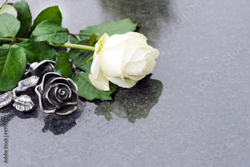 Weisse Rose und Rose aus Bronze auf Grabplatte, copyspace