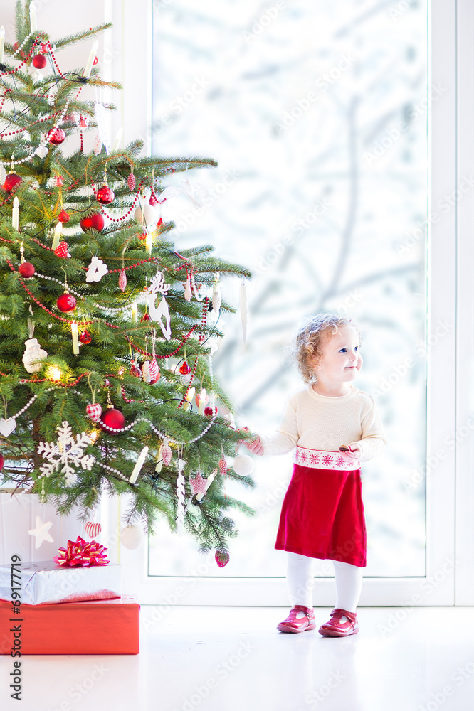 Adorable toddler girl  decorating Christmas tree