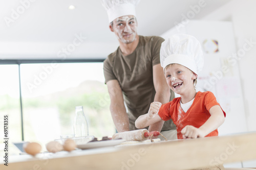 a father and his son preparing a cake in the kitchen