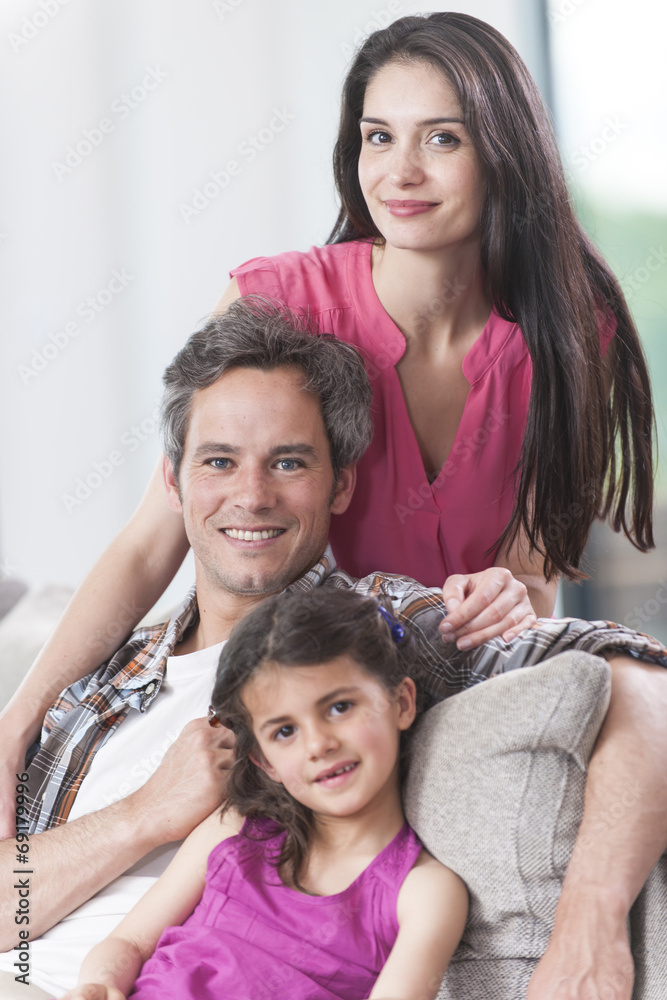 smiling family on a couch looking at camera smiling family on a couch looking at camera