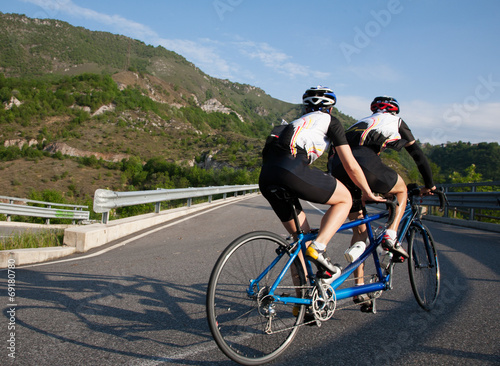Cyclists on a Tandem bicycle riding uphill on a mountain roadway