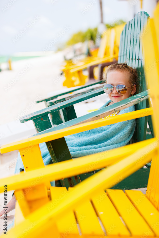 Little girl relaxing in colorful chair at beach