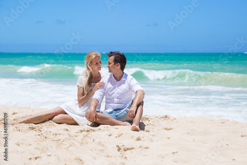 Cheerful couple embracing and posing on the beach on a sunny day