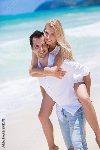 Happy young couple enjoying a solitary beach backriding photo