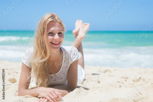 Smiling young girl lying on the sunny beach