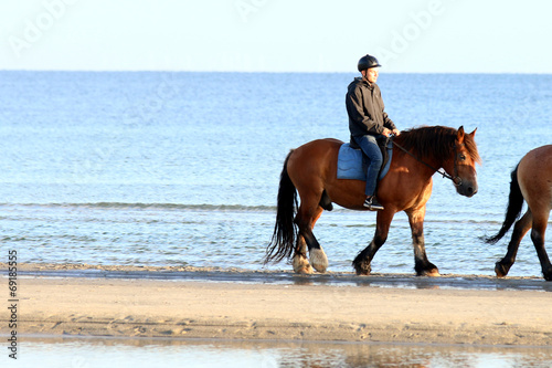 Junge mit Pferd reitet am Strand entlang © Osterland