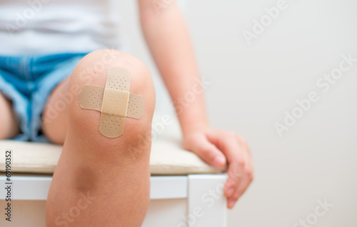 Child knee with an adhesive bandage and bruise. Fototapet