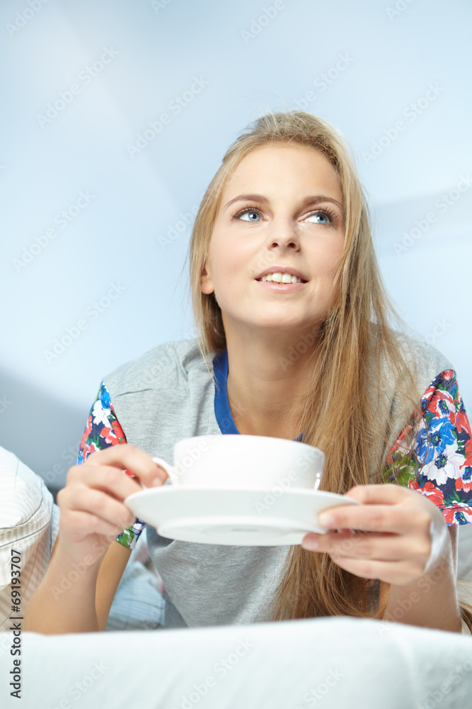 Attractive woman with a cup of coffee on the bed