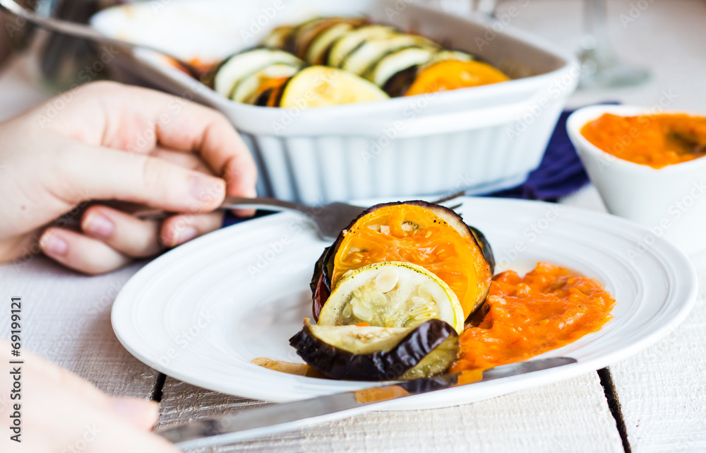 processes food ratatouille in a circular plate, hand processes food ratatouille in a circular plate, hand
