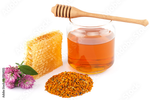 Honey in jar with dipper, honeycomb, pollen and flowers